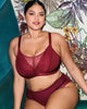 Elomi Tiernie Wirefree bralette and brief in Tibetan Red lace and mesh made for the curvy busty woman sitting on a teal velvet lounge with botanical wallpaper behind