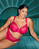 Matilda Plunge bra and Brazilian in Hot Pink made for the curvy full bodied big boobed woman lifestyle image sitting on teal velvet lounge